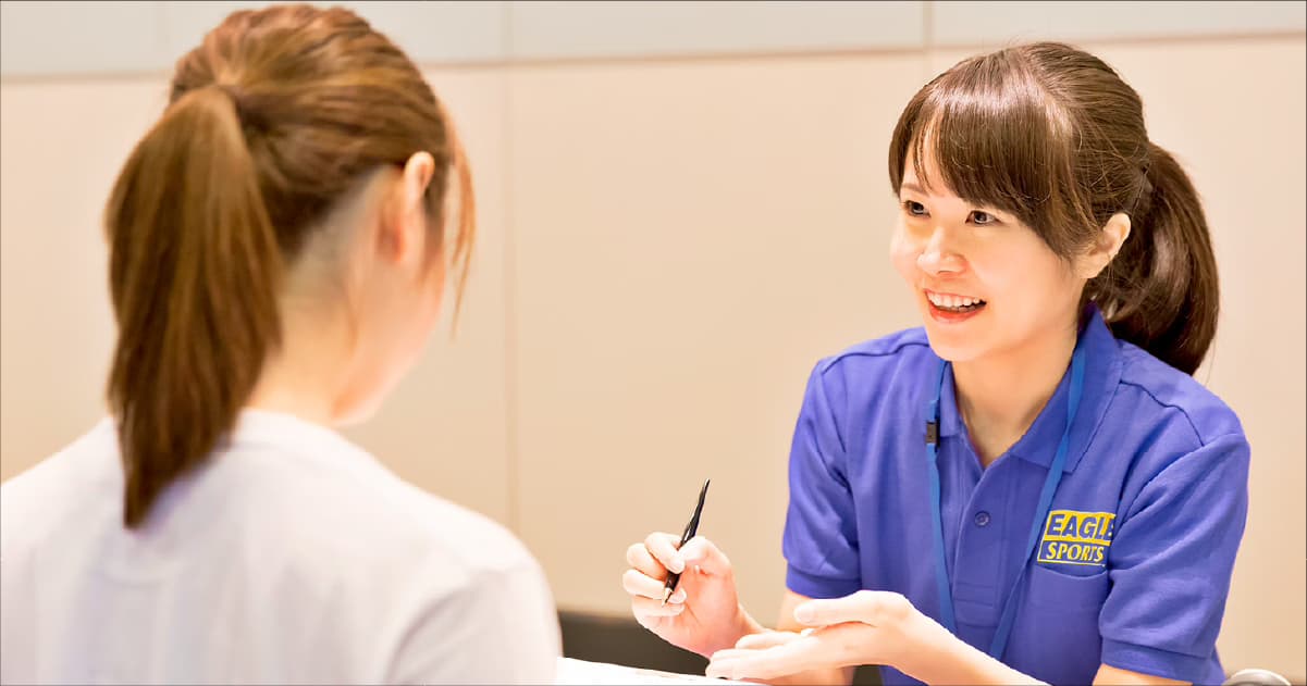 笑顔で接客する青いユニフォームのスタッフ