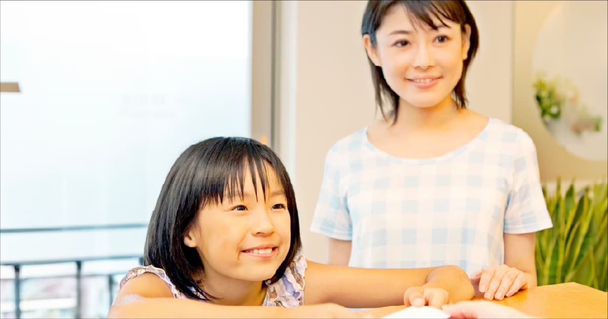 笑顔の親子がフロントで受付をしている様子