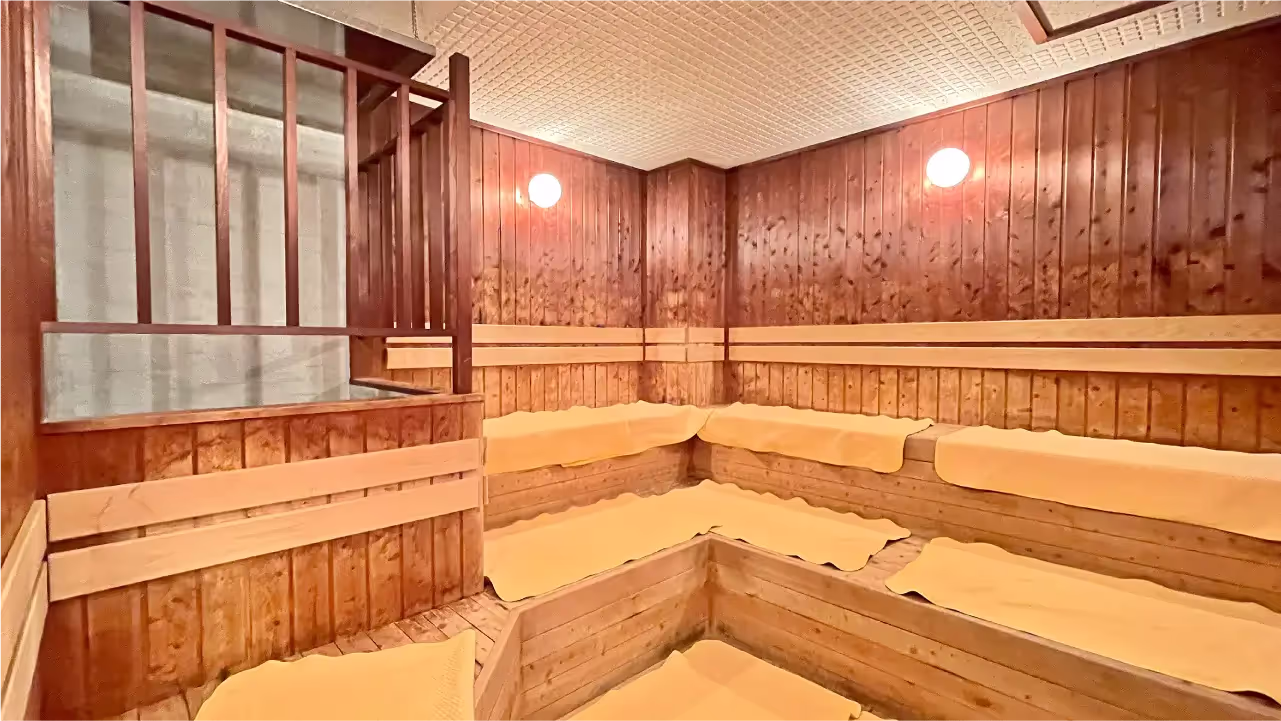 木製の壁とベンチに黄色いマットが敷かれた室内サウナ。