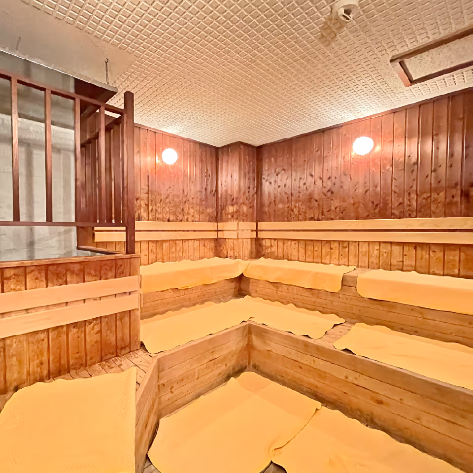 木製の壁とベンチに黄色いタオルが敷かれた空のサウナルーム。