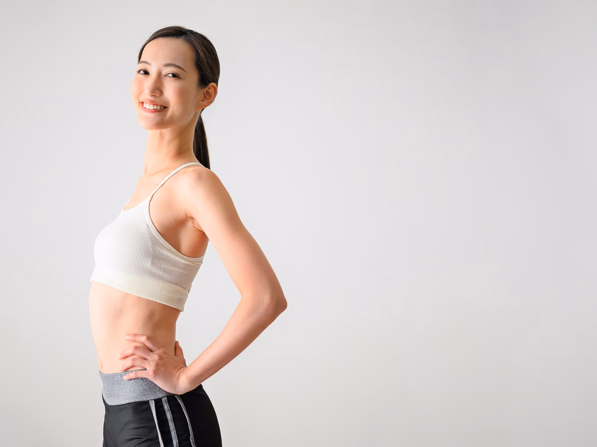 腰に手を当てて立ち、姿勢を確認する女性。