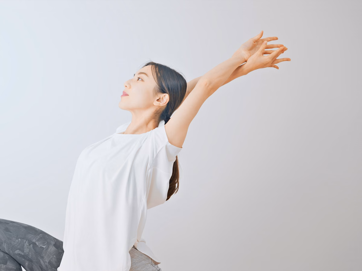 両腕を斜め上に伸ばす女性。